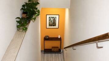 Eine Treppe mit einer Holzhandläufe, eine kleine Ablagefläche mit einer Schale und einer Kerze sowie ein gerahmtes Bild an der Wand.