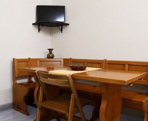 A dining area with a wooden table and benches, a flat-screen TV mounted on the wall, and a decorative vase on the wall. - WOW San Miniato! 2 Bedrooms Central Apartment (San Miniato)