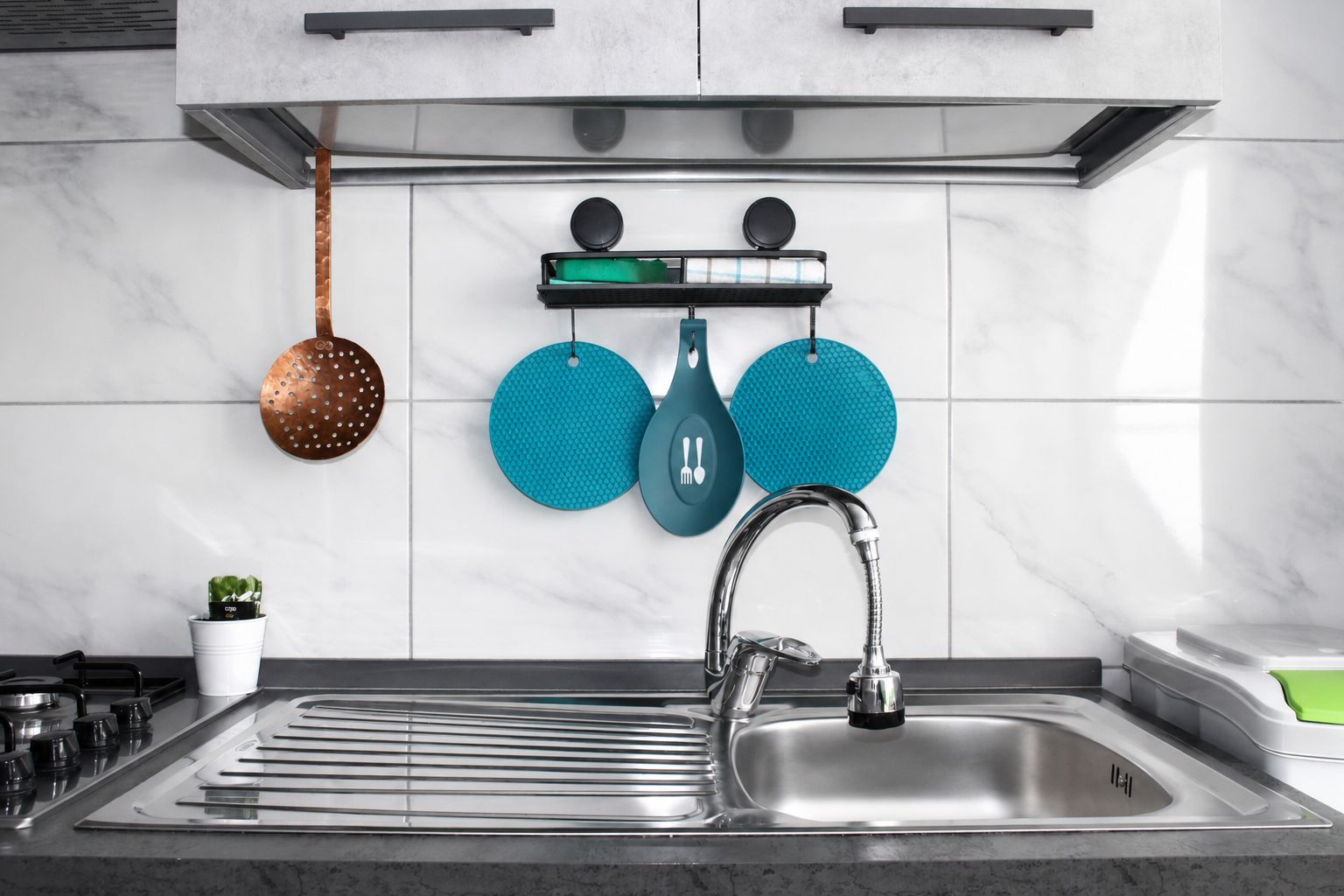 Una cucina moderna con un lavandino in acciaio inossidabile, una selezione di pentole e padelle, e una piccola pianta in vaso.