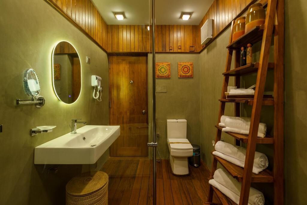A bathroom with a wooden vanity, a sink, a mirror, a toilet, and a towel rack.