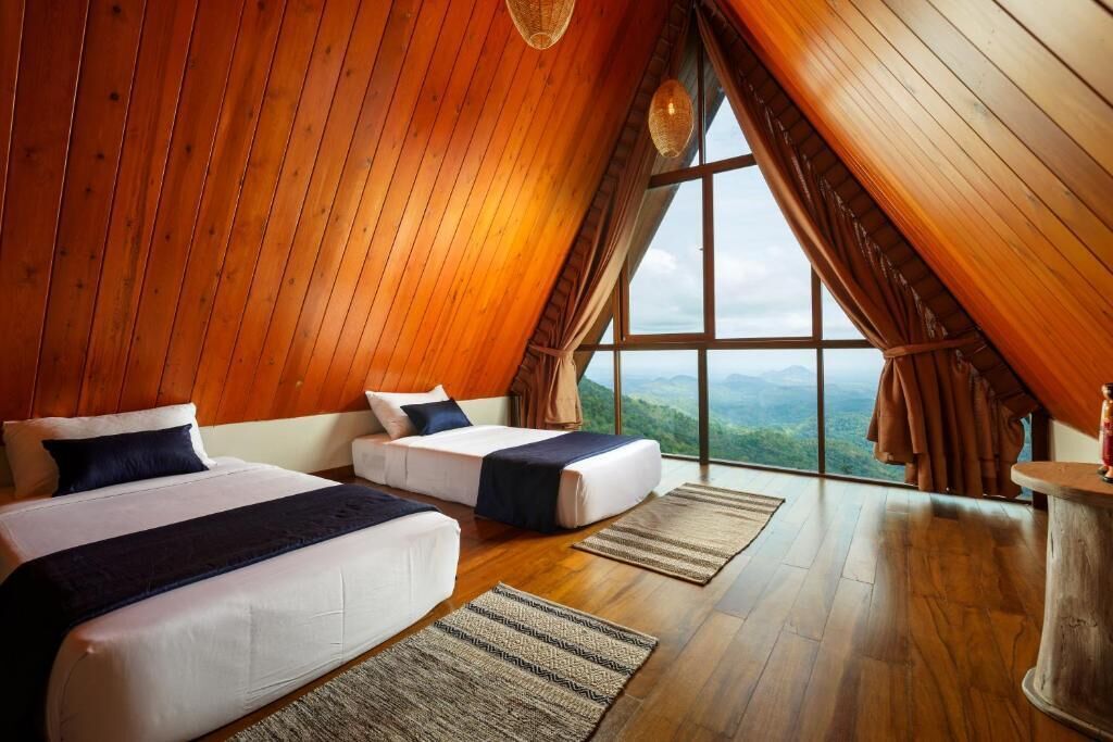 A high-ceilinged room with wooden walls and a large window offering a mountain view.