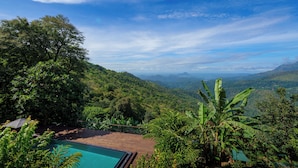 A pool surrounded by lush greenery and a mountainous landscape.
