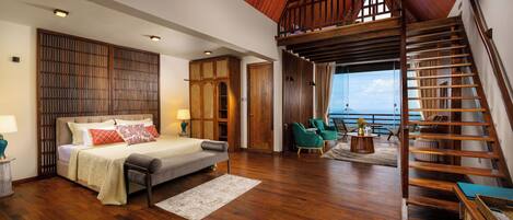 Un dormitorio espacioso con una cama grande, una escalera de madera y vista al mar.
