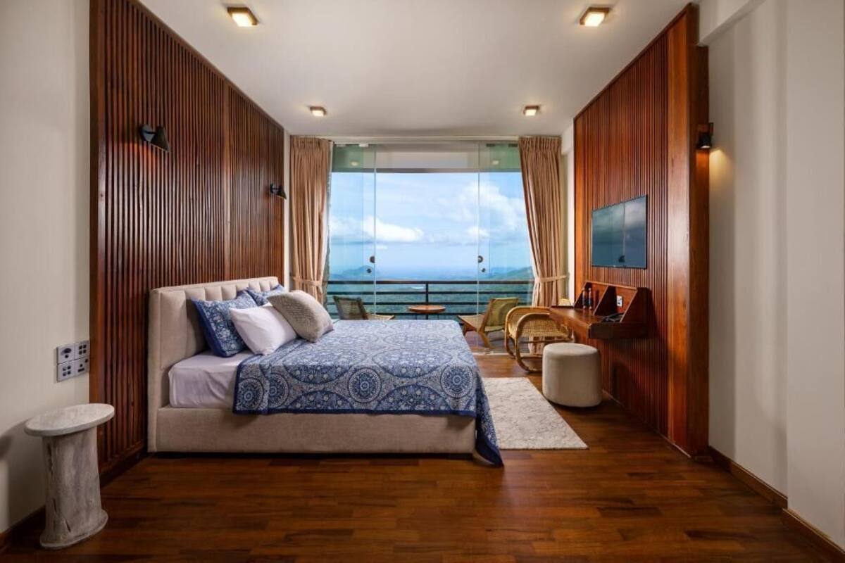 Un dormitorio con cama, televisor, balcón y vistas, además de paneles de madera.