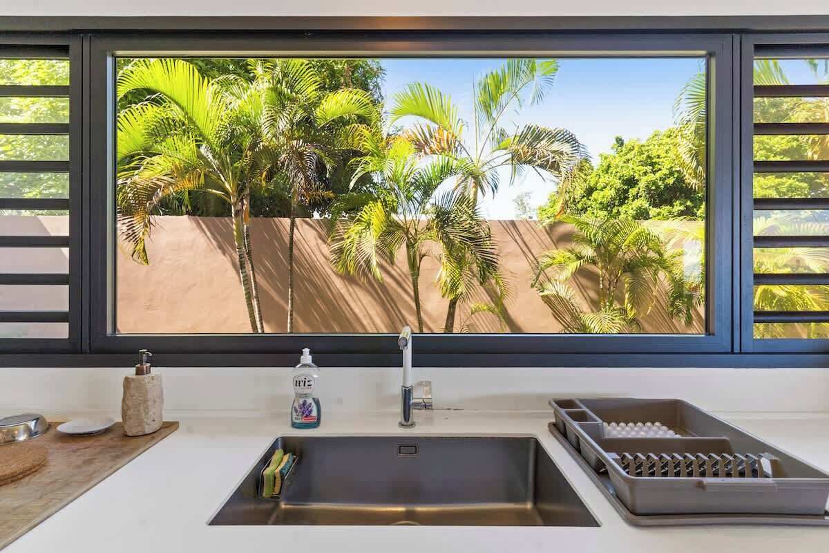 A kitchen with a large window, a sink, and a dish rack.