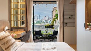 Een moderne slaapkamer met uitzicht op de stad, een balkon met stoelen en een groot raam met gordijnen.