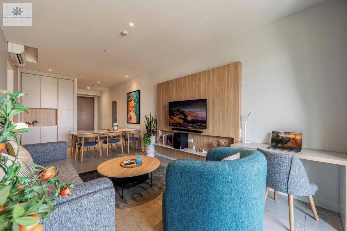 Ein modernes Wohnzimmer mit Sofa, Couchtisch, Wand-Fernseher und einem Essbereich mit Stühlen und Tisch.