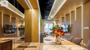 Een modern interieur met houten lambrisering, een eethoek met een gedekte tafel voor twee personen, en een televisie aan de linkerkant.