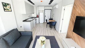 A modern apartment with a living room, kitchenette, dining area, and a TV. - Moon City (Antalya)