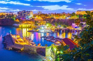 A coastal cityscape with a harbor, buildings, and a fortified wall. - Moon City (Antalya)