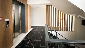 A modern interior with a wooden door, a staircase with wooden railings, and a black marble floor. - Moon City (Antalya)