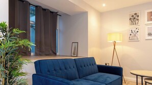 Ett modernt vardagsrum med en blå soffa, en golvlampa och en mönstrad matta.
