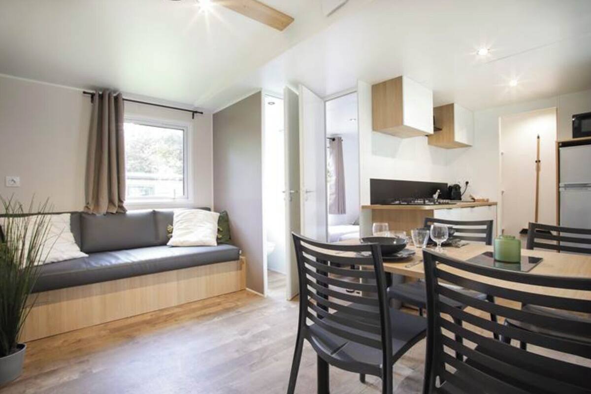Un espacio habitable moderno y funcional con zona de estar, mesa de comedor y kitchenette.