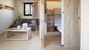Habitació amb un sofà, una taula de cafè, una planta, una escala i un llit superposat.