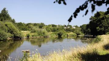 A river with surrounding greenery and a few houses in the background.