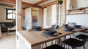 Una cuina moderna amb bigues de fusta, una taula de menjador preparada amb bols i plats, caires negres i una estantenca amb objectes decoratius.