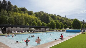 Una piscina envoltada per una zona verda amb gandules i un edifici al fons.
