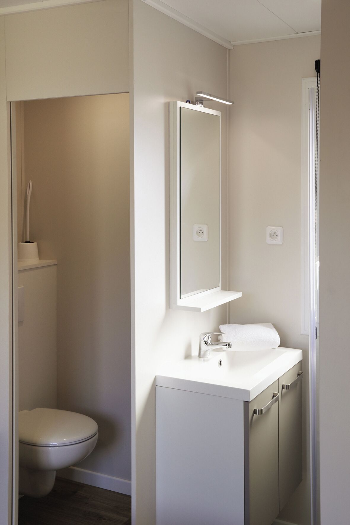 Un baño con inodoro, lavamanos y espejo.