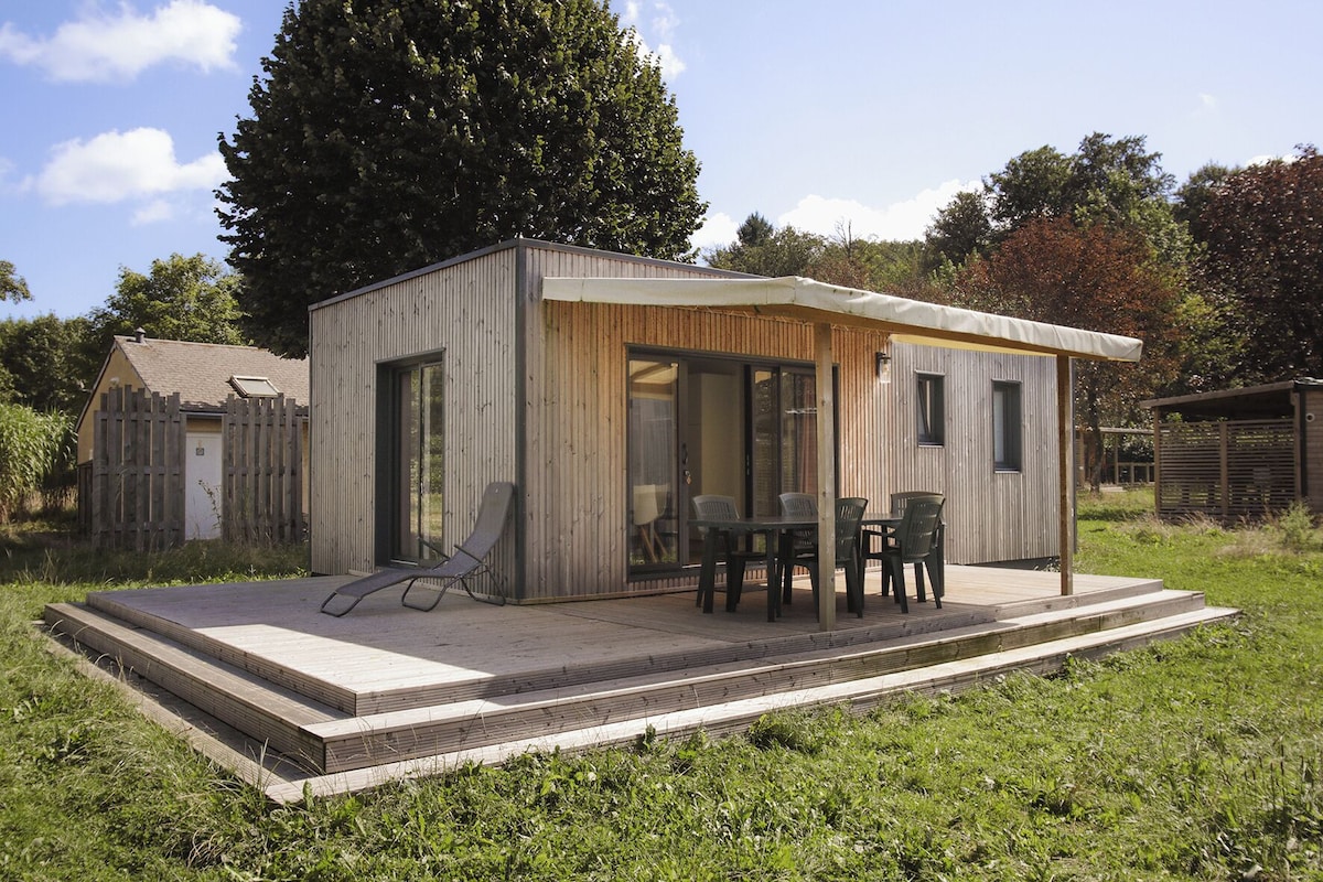 A modern outdoor structure with a patio, a table with chairs, and a lounge chair.
