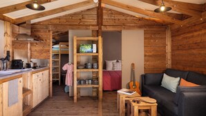 Interior acollidor d'una cabana amb cuina, zona de dinar i saló.