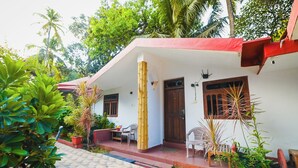 A house with a red roof, white walls, and a tiled porch. There are potted plants and a bench outside. - Harbor Court Vagator (Vagator)