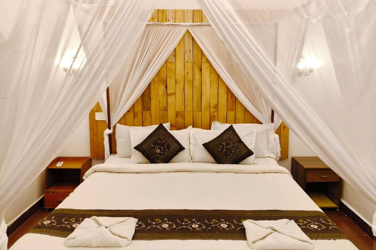 A bed with white linens, two dark pillows, and a canopy.