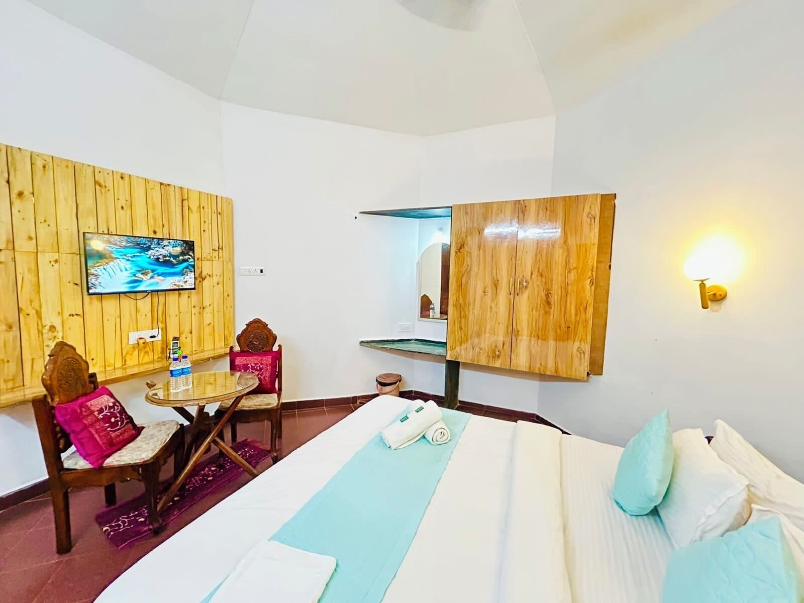 Ein Hotelzimmer mit einem Bett, einem Schreibtisch mit Stuhl, einem Wandfernseher und einem Holzschrank.