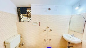 A small bathroom with a toilet, sink, and shower. - Harbor Court Vagator (Vagator)
