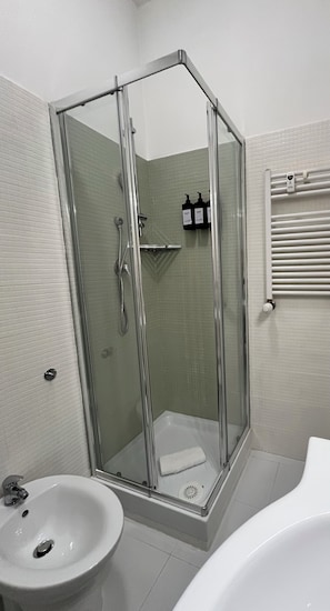 A modern bathroom with a glass-enclosed shower, a white sink, and a bathtub.