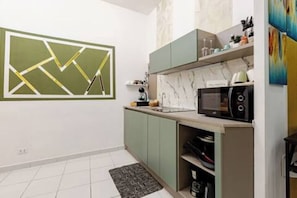 Una cucina compatta con forno a microonde, mobili e una schiena di marmo.