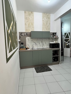 A modern kitchen with a marble backsplash, green cabinets, and a built-in microwave.