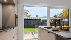 A modern kitchen with a large window, wooden flooring, and a view of a backyard. - "Barnet" - 180m to the fjord by Interhome (Storvorde)