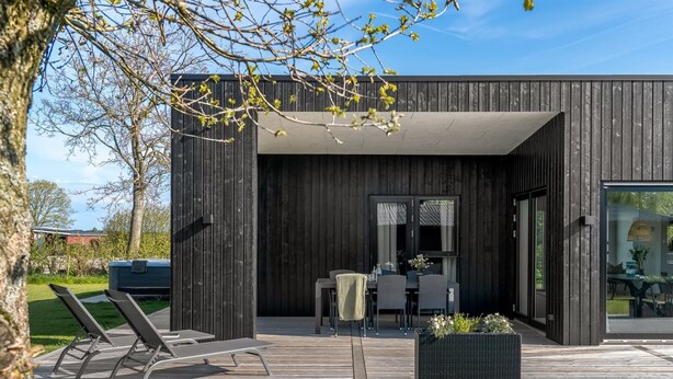 A modern building with a deck, outdoor seating, and a large window. - "Barnet" - 180m to the fjord by Interhome (Storvorde)