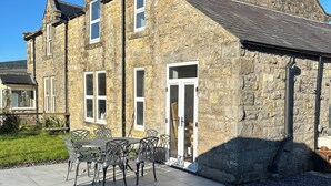 A stone building with a tiled patio and outdoor seating.