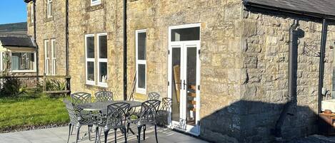 A stone building with a tiled patio and outdoor seating.