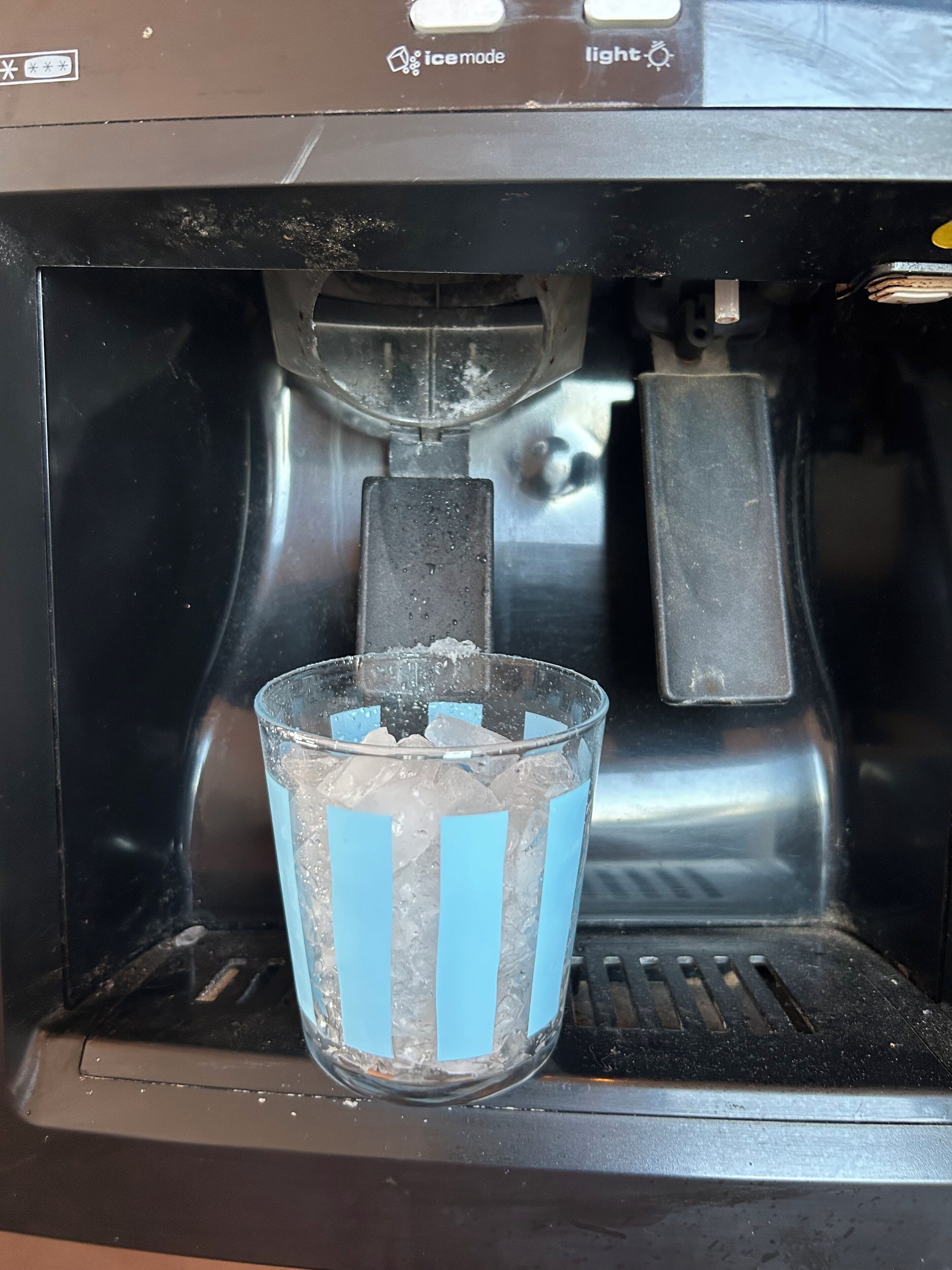 A coffee machine with a glass cup filled with ice cubes.