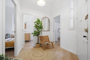 Un pasillo con un banco de madera, una planta en maceta y un espejo en la pared.