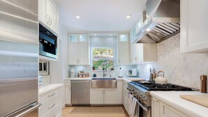 A modern kitchen with stainless steel appliances, white cabinetry, and a window providing natural light.