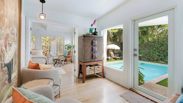 A spacious living area with a pool view, a large painting, and a wooden cabinet with decorative items.