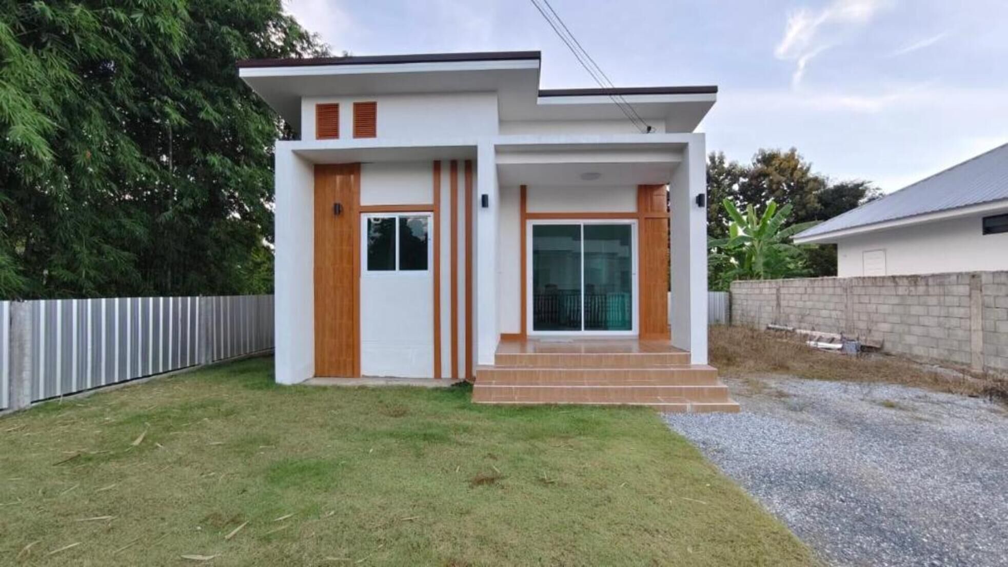 Une maison moderne à deux étages, dotée d’un toit plat, de grandes portes-fenêtres coulissantes et d’un petit porche à l’avant.