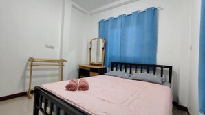 Une chambre à coucher avec un lit, une table de chevet en bois, un miroir et un rideau bleu.