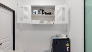 Une cuisine compacte dotée d’un meuble intégré contenant une bouilloire, une casserole et de la vaisselle empilée.