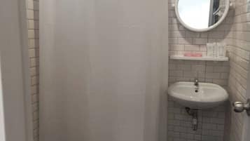 Un baño pequeño con cortina de ducha, inodoro, lavamanos y ventana.