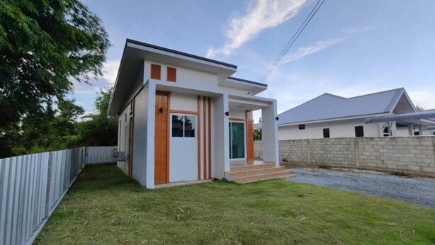 Une maison moderne à deux étages, dotée d’un toit plat, d’un porche à l’avant et d’un petit jardin devant.