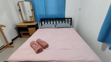 Quarto com cama, mesa de cabeceira de madeira, espelho e cortinas azuis.