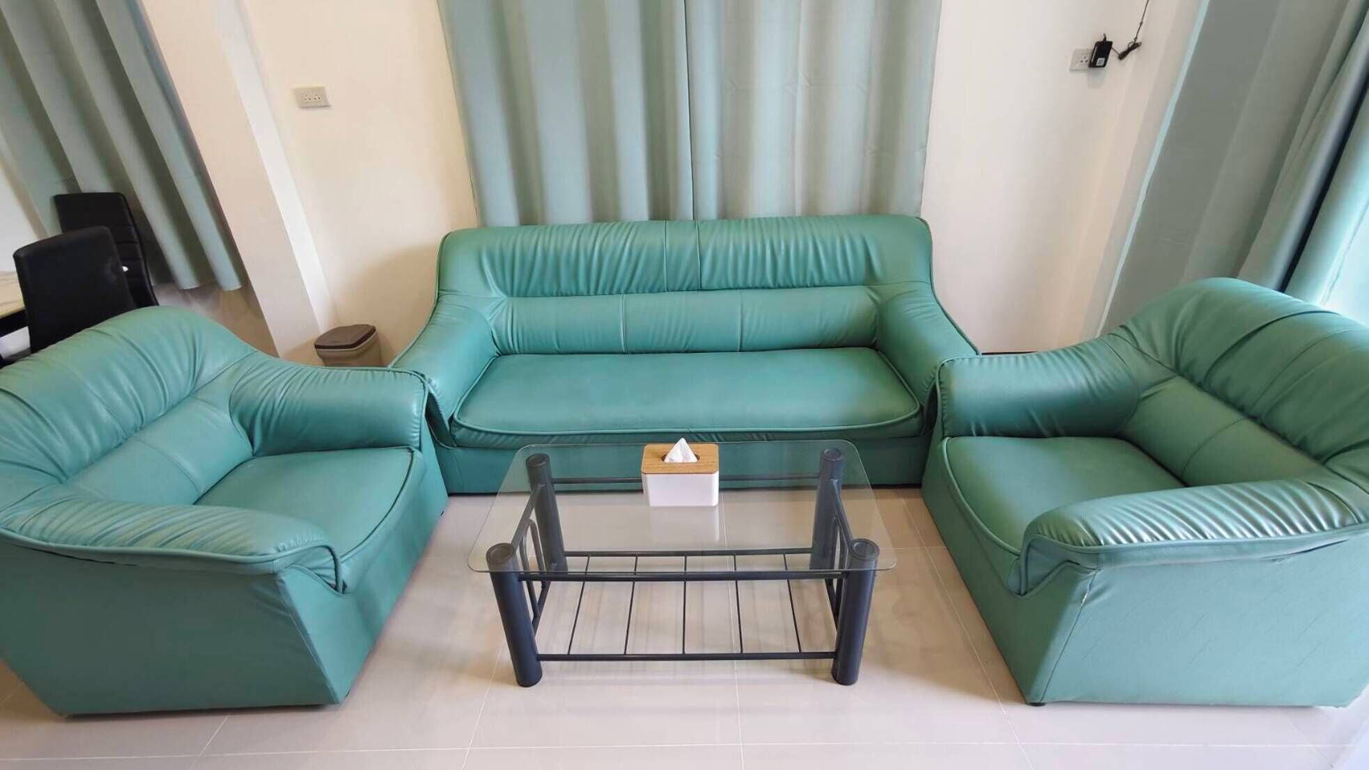 A living room with a teal sofa set, a coffee table, and a small side table.