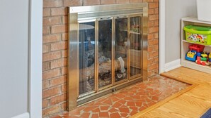 A modern living room with a fireplace, a flat-screen TV mounted above it, and a toy shelf to the right. - *Pet Friendly* Charming-Single story | Fenced Yard, Outdoor Dining, Near Duke (Durham)