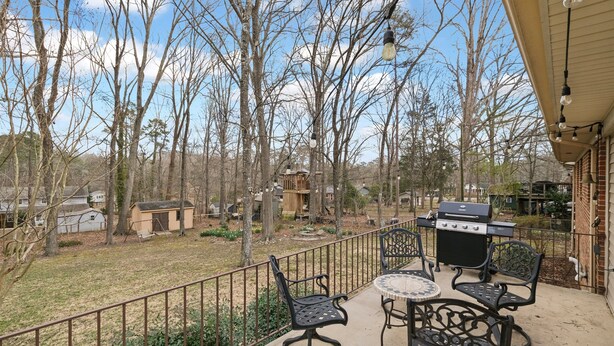 A patio with outdoor furniture, a grill, and a view of a wooded area. - *Pet Friendly* Charming-Single story | Fenced Yard, Outdoor Dining, Near Duke (Durham)