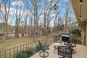 A patio with outdoor furniture, a grill, and a view of a wooded area. - *Pet Friendly* Charming-Single story | Fenced Yard, Outdoor Dining, Near Duke (Durham)