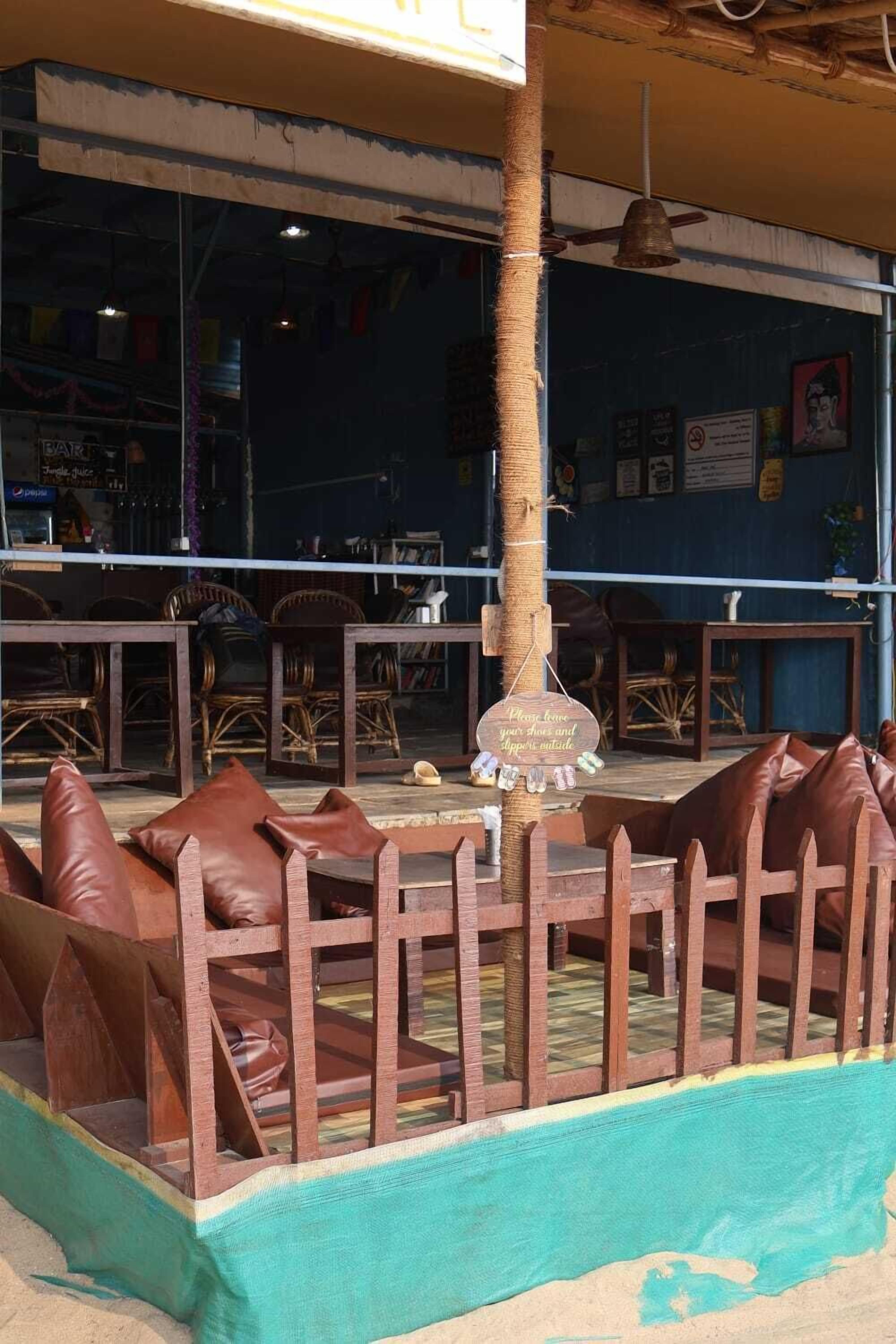Un espacio al aire libre con bancos de madera y una mesa central, rodeado por un bajo cerco de madera.